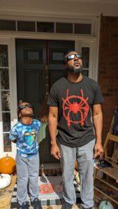 Father and Son looking up at the eclipse while wearing eclipse glasses.